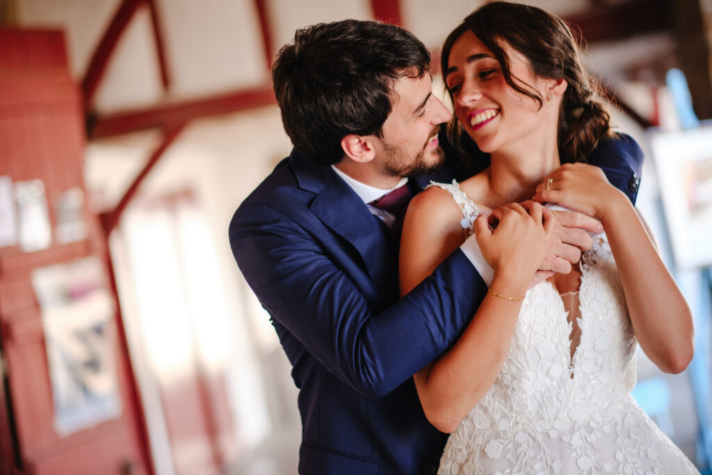Mariage aux Collines Iduki Les mariés enlacés devant une façade basque aux volets rouges.