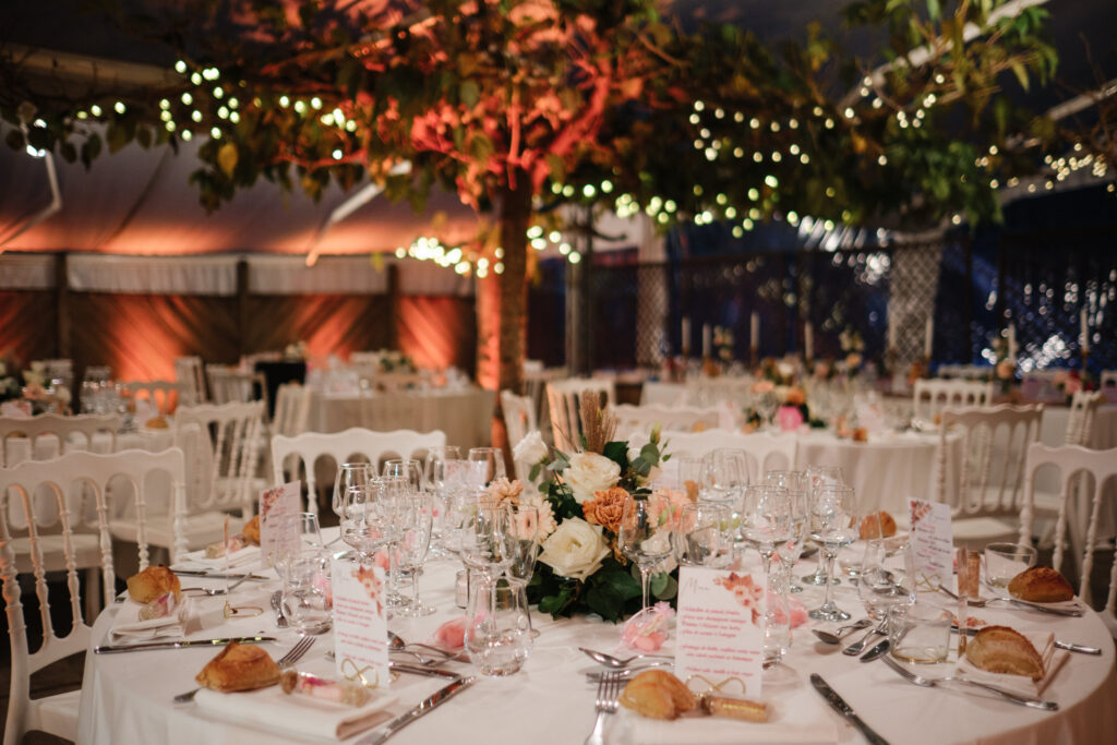 Mariage aux Collines Iduki Tables de mariage fleuries sous les guirlandes lumineuses de la réception.
