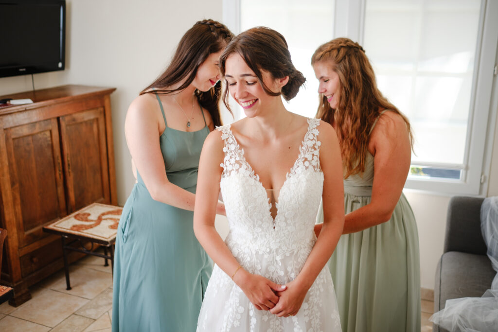 Mariage aux Collines Iduki La mariée souriante pendant ses préparatifs, accompagnée de deux proches.