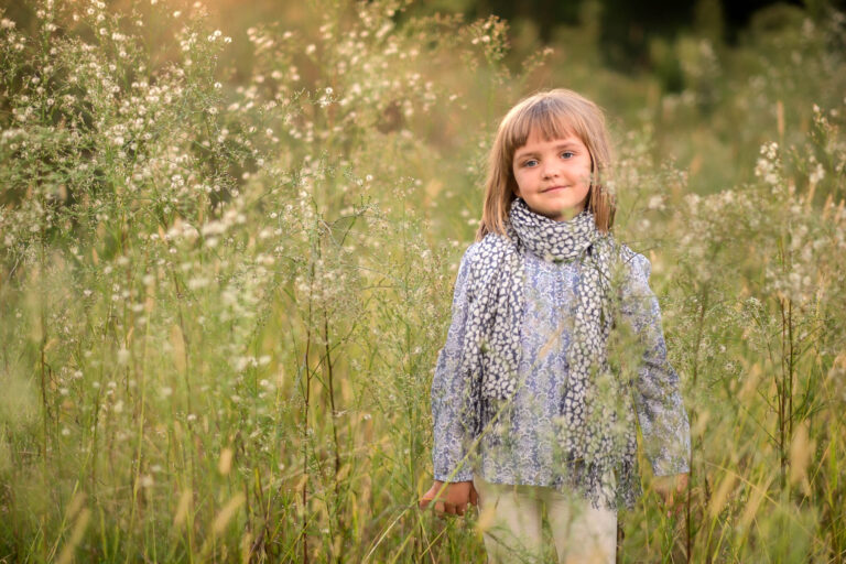 Une enfant en robe claire debout dans les hautes herbes