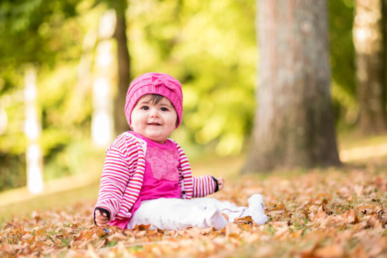 Une petite fille en rose assise près d’un arbre