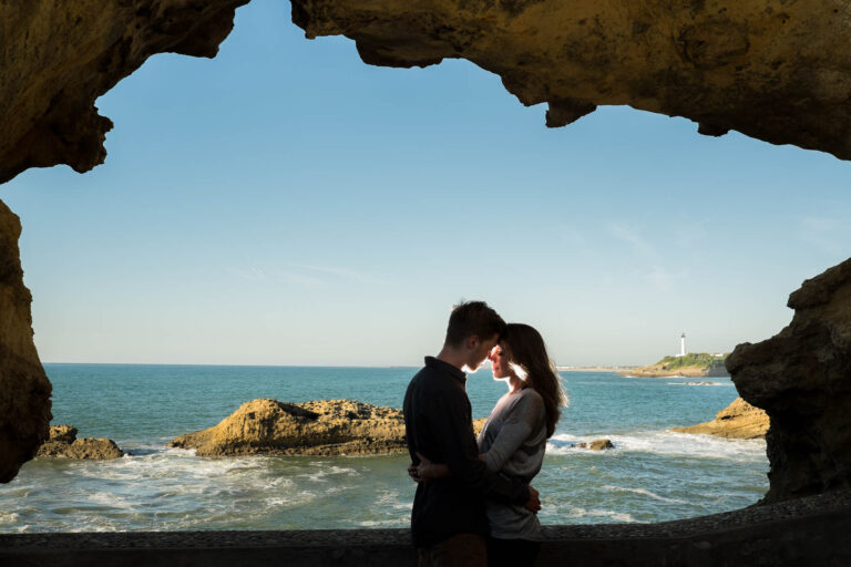 Un couple s’embrasse à l’entrée d’une grotte face à la mer