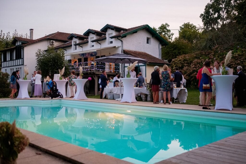 Les invités près de la piscine à la tombée du jour lors du mariage d’Amanda et Rémi