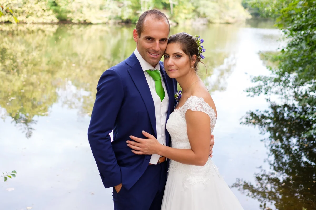 Clémence et Mathieu enlacés devant un plan d’eau pendant leur mariage